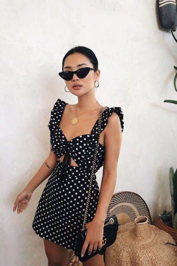 image of a woman in a polka dot mini dress with sunglasses and a designer handbag