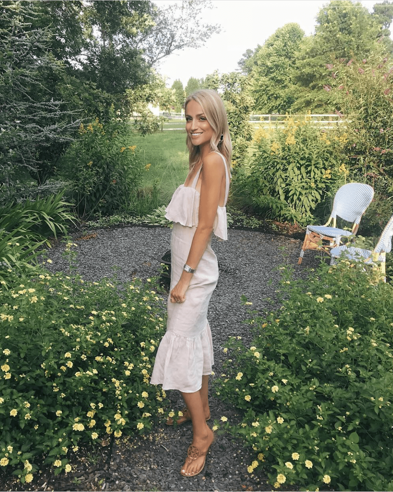 image of a woman in a white linen midi dress standing in a garden area