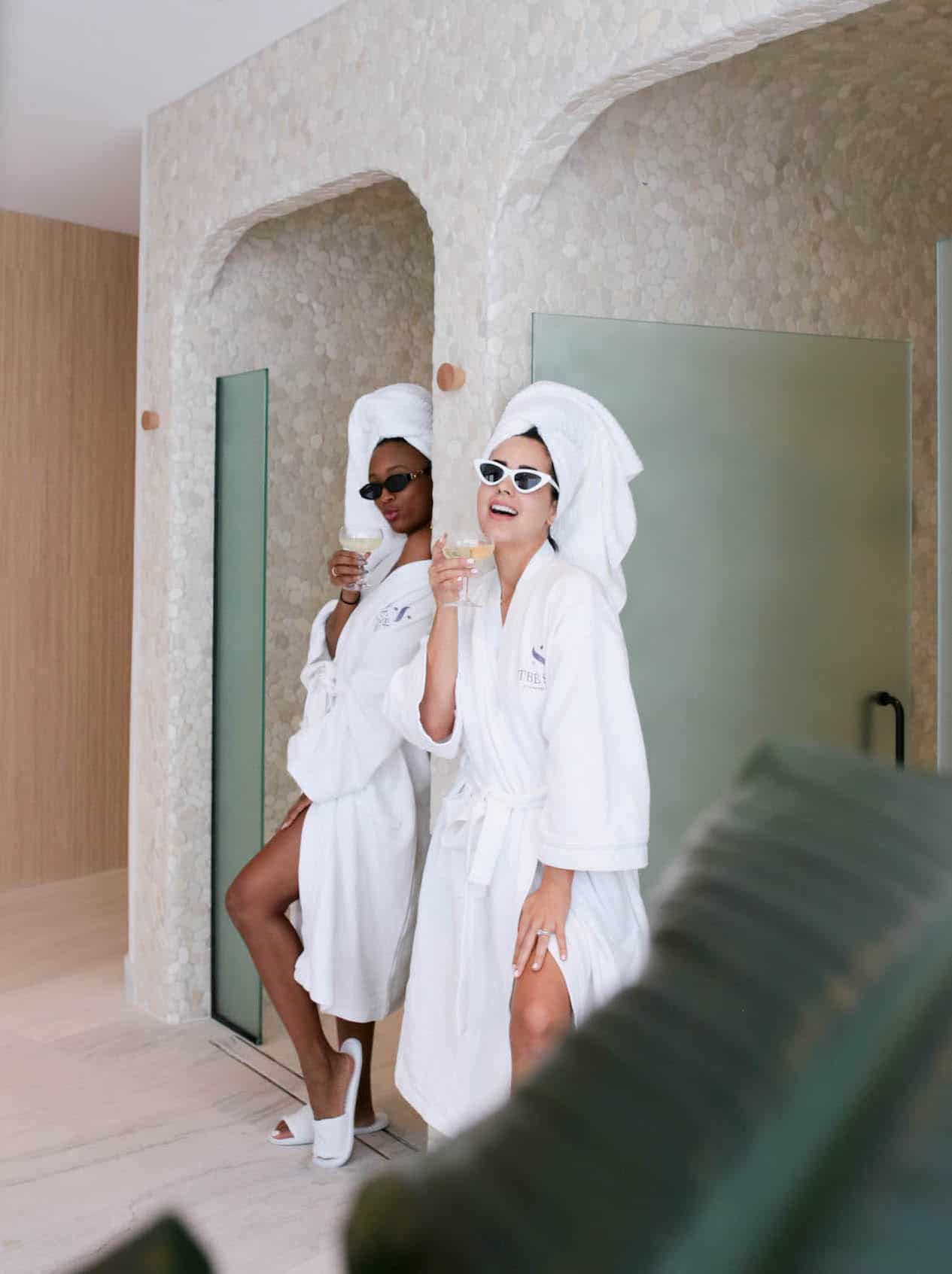 image of two women dressed in white robes with towels on their heads in a spa shower room