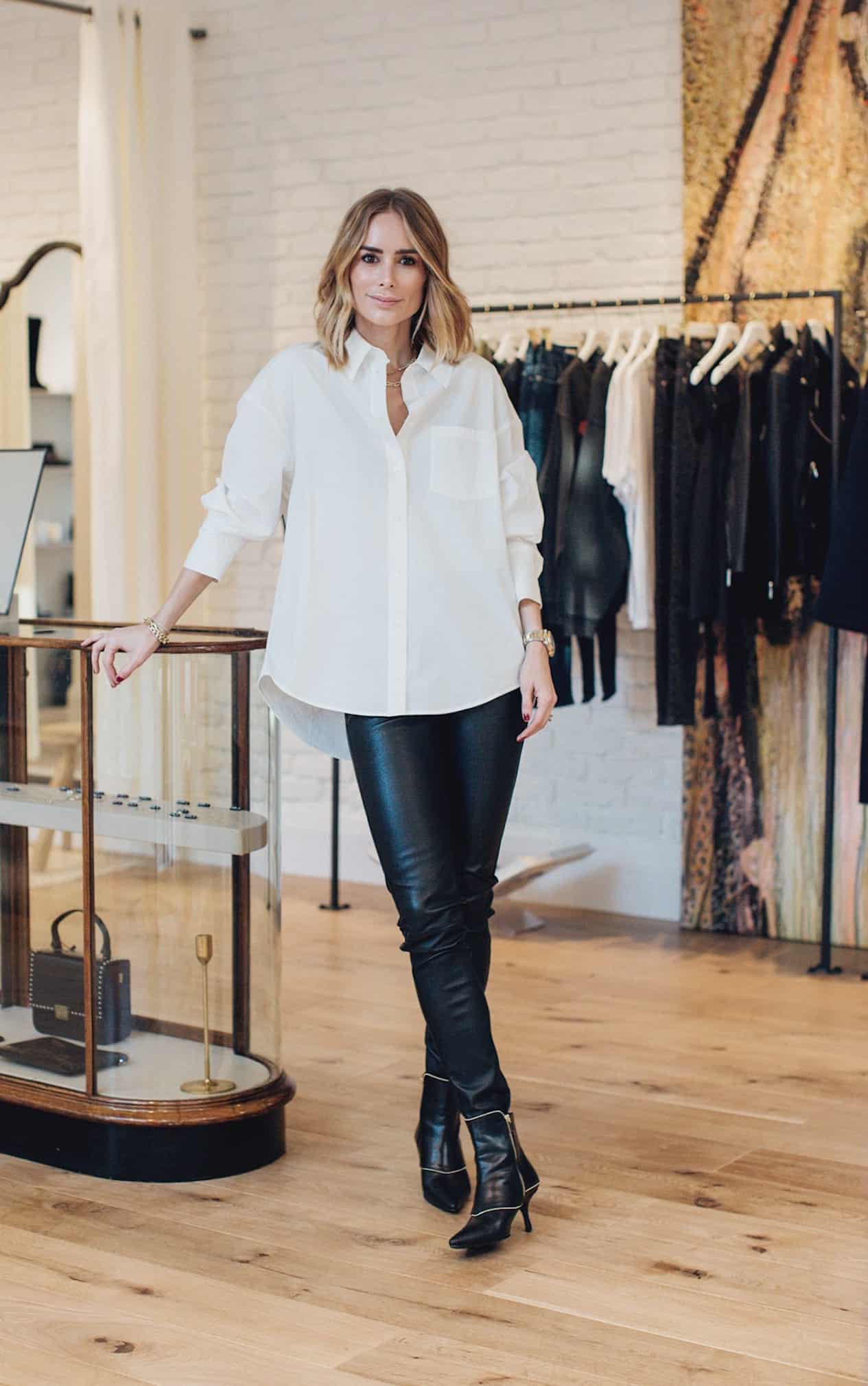 image of a woman wearing a white button down shirt, black leather leggings, and black ankle boots in a clothing store