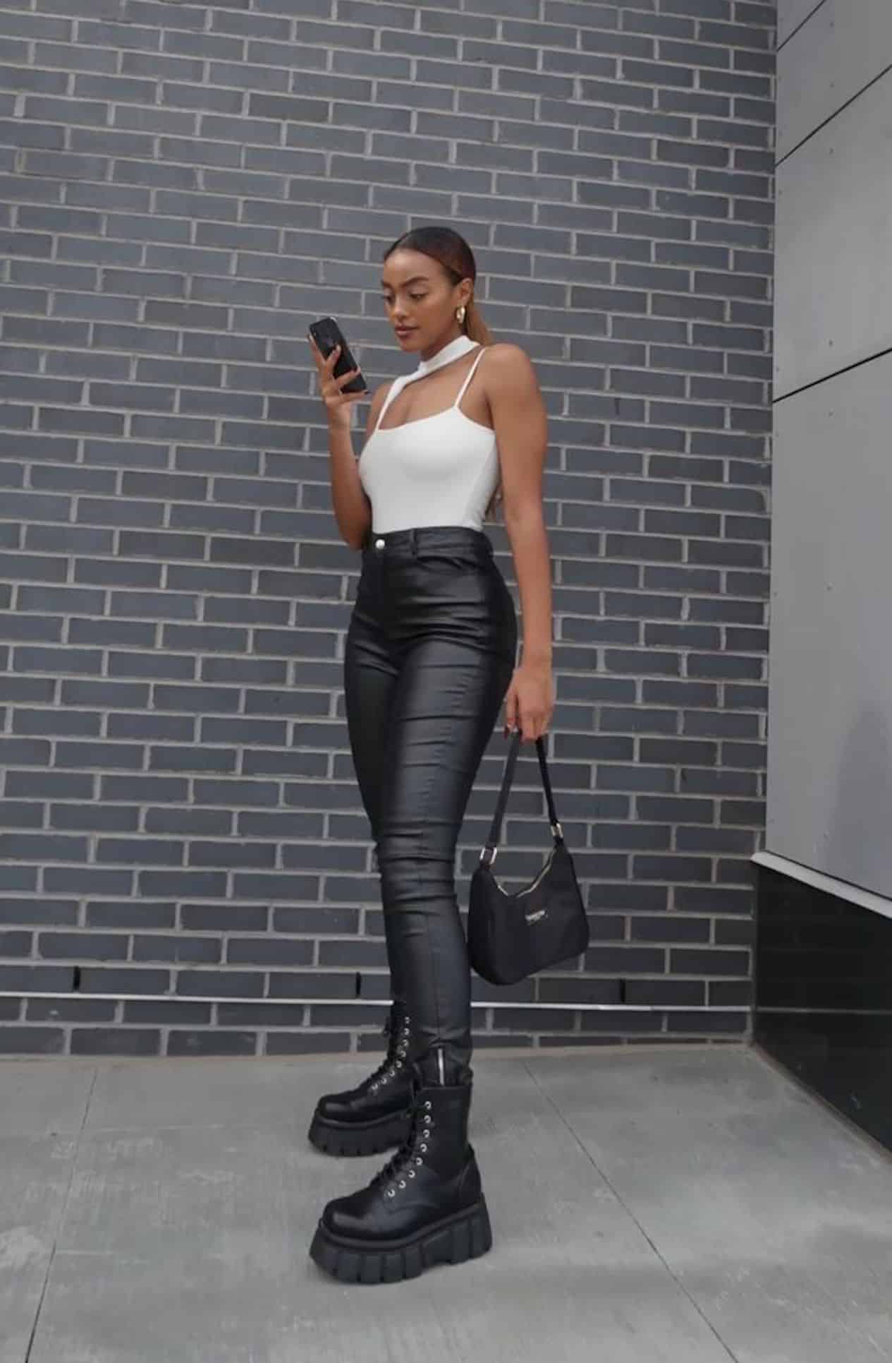image of a woman in black leather leggings and a white body contour tank top with black combat boots