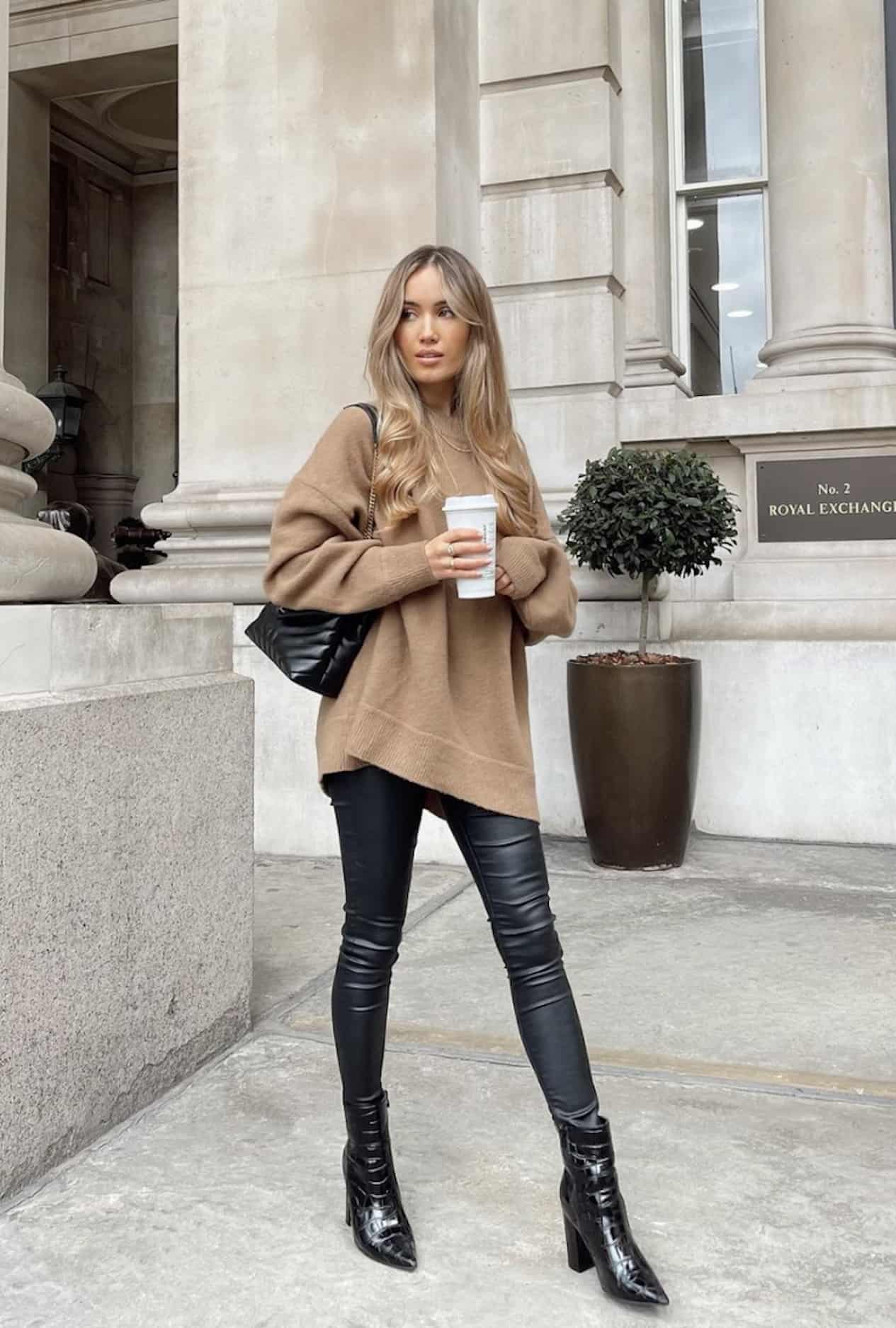image of a woman wearing an oversized camel sweater and black leather leggings with black booties