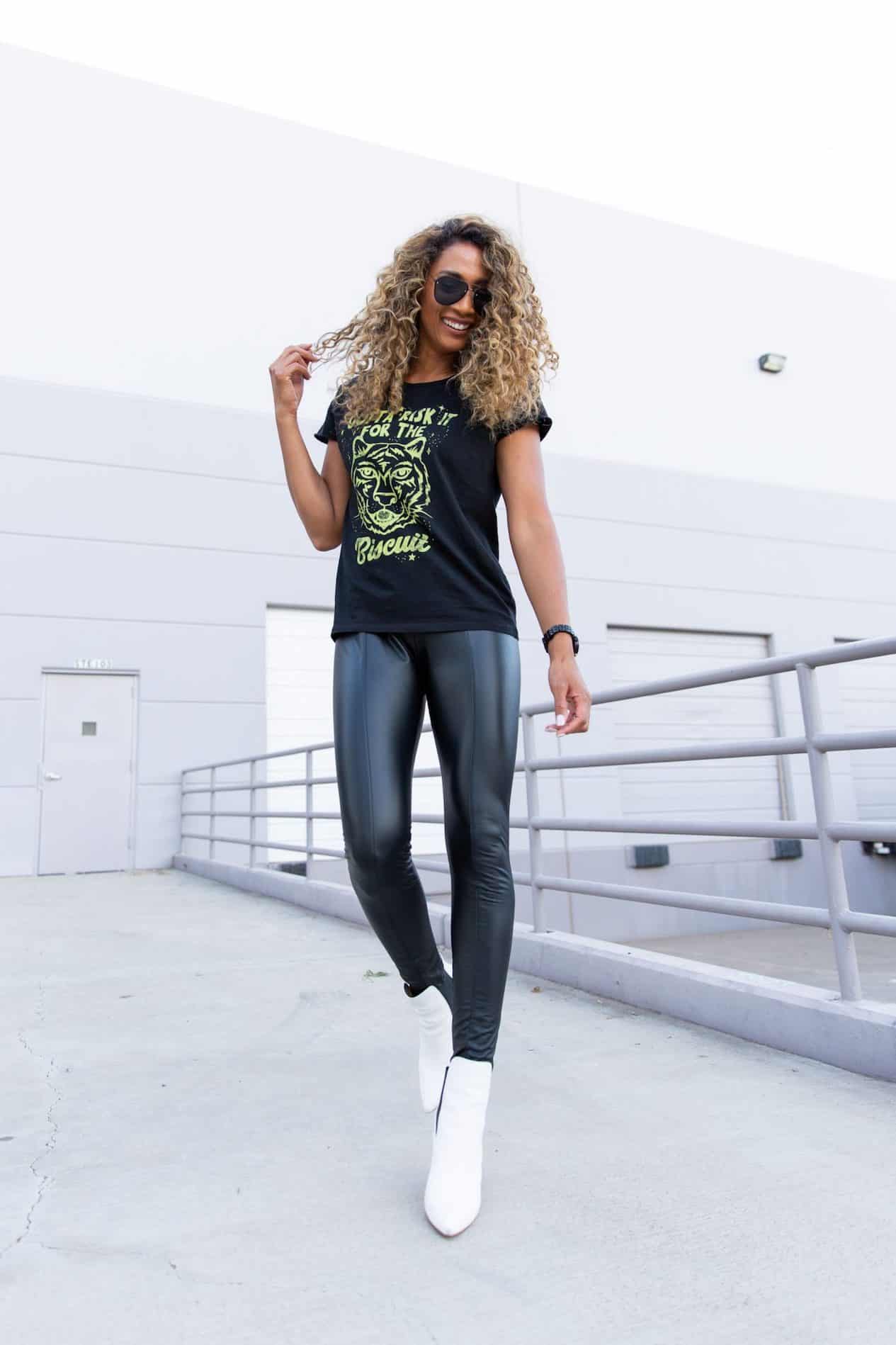 image of a woman wearing a graphic t-shirt, leather leggings, and white sneakers