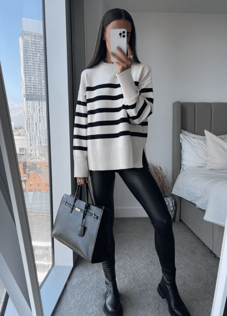 image of a woman in a striped white and black oversized sweater, leather leggings, and black boots