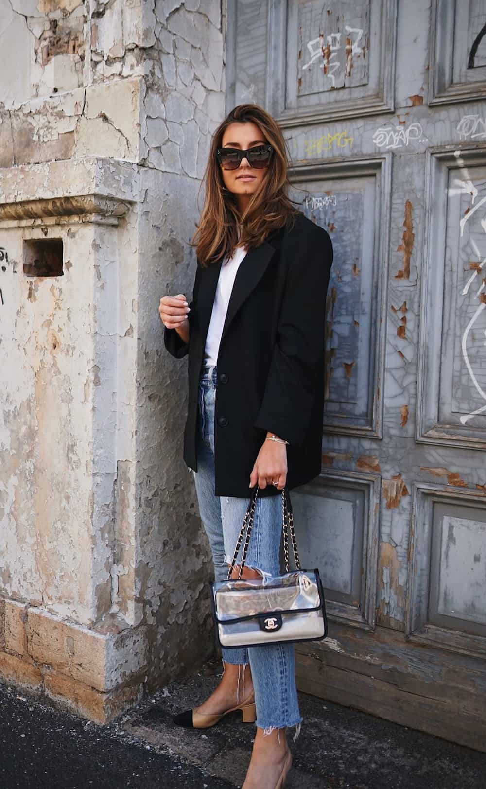 image of a woman in an oversized black blazer, white t-shirt, jeans, and low heels