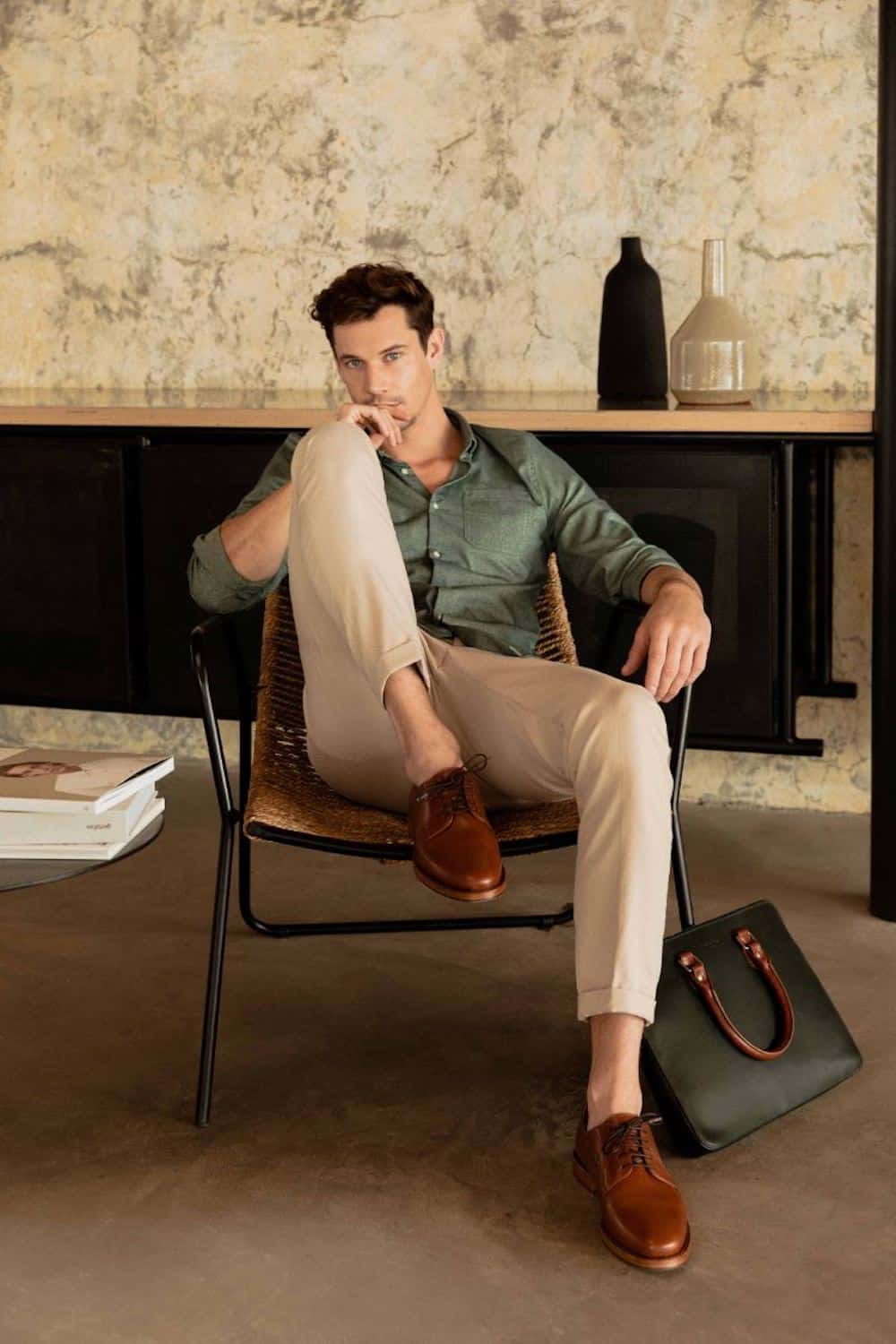 image of a good looking man sitting in a chair wearing brown shoes, khaki pants, and a forest green button up shirt