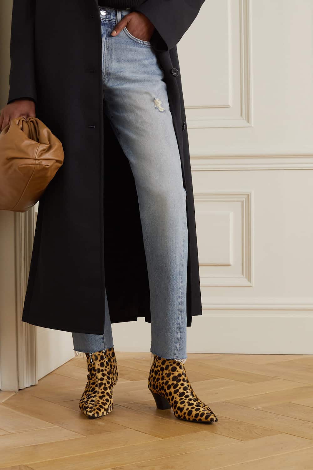 image of a woman wearing faded blue jeans, a black coat, and cheetah print ankle boots