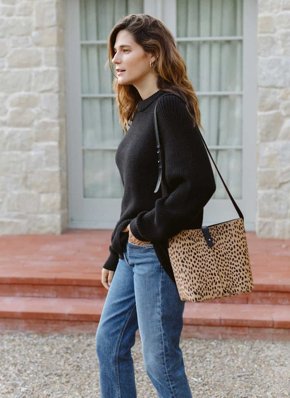 image of a woman in a black sweater and jeans with a cheetah print pony hair bucket bag