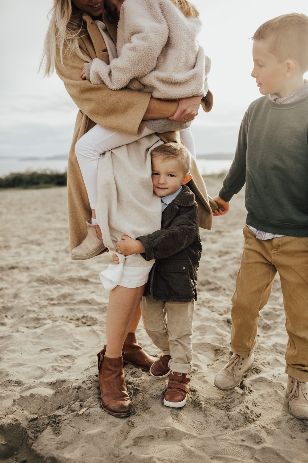 image of a family photoshoot in the fall with two small boys and a mom holding another child, everyone dressed in neutral colors