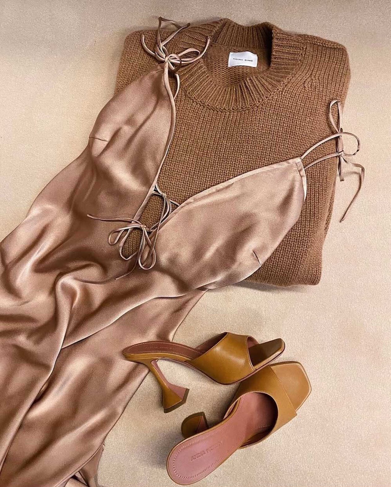 Flat lay of a silk dress, sweater and heels.