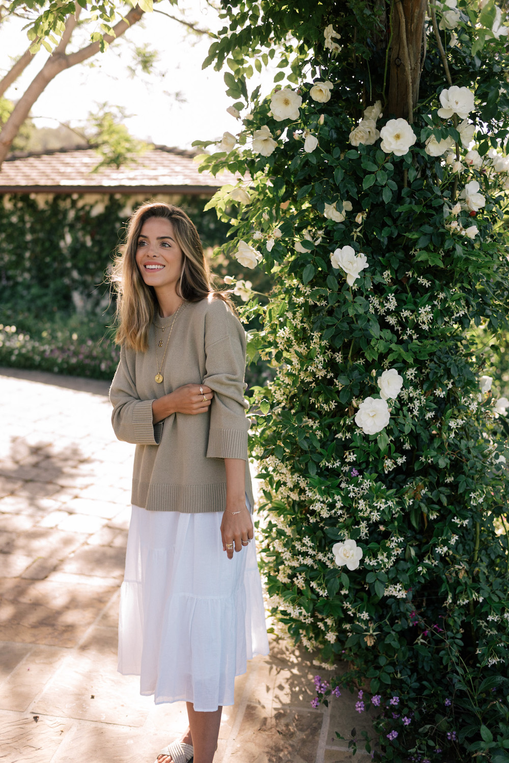 image of a woman in a white sundress with a green oversized sweater over it