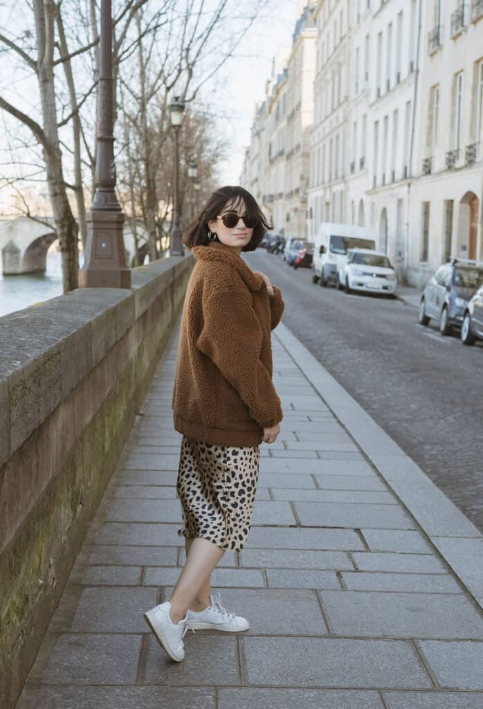image of a woman in a shearling coat and leopard print midi skirt with sneakers