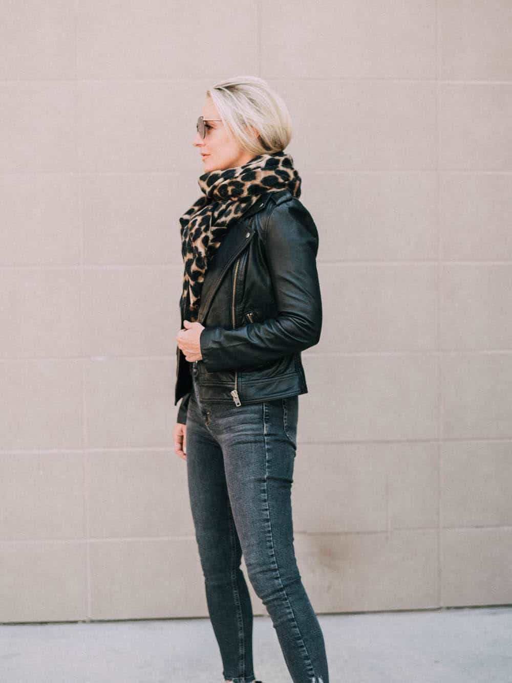 image of a woman in a black leather jacket and black jeans with a leopard scarf