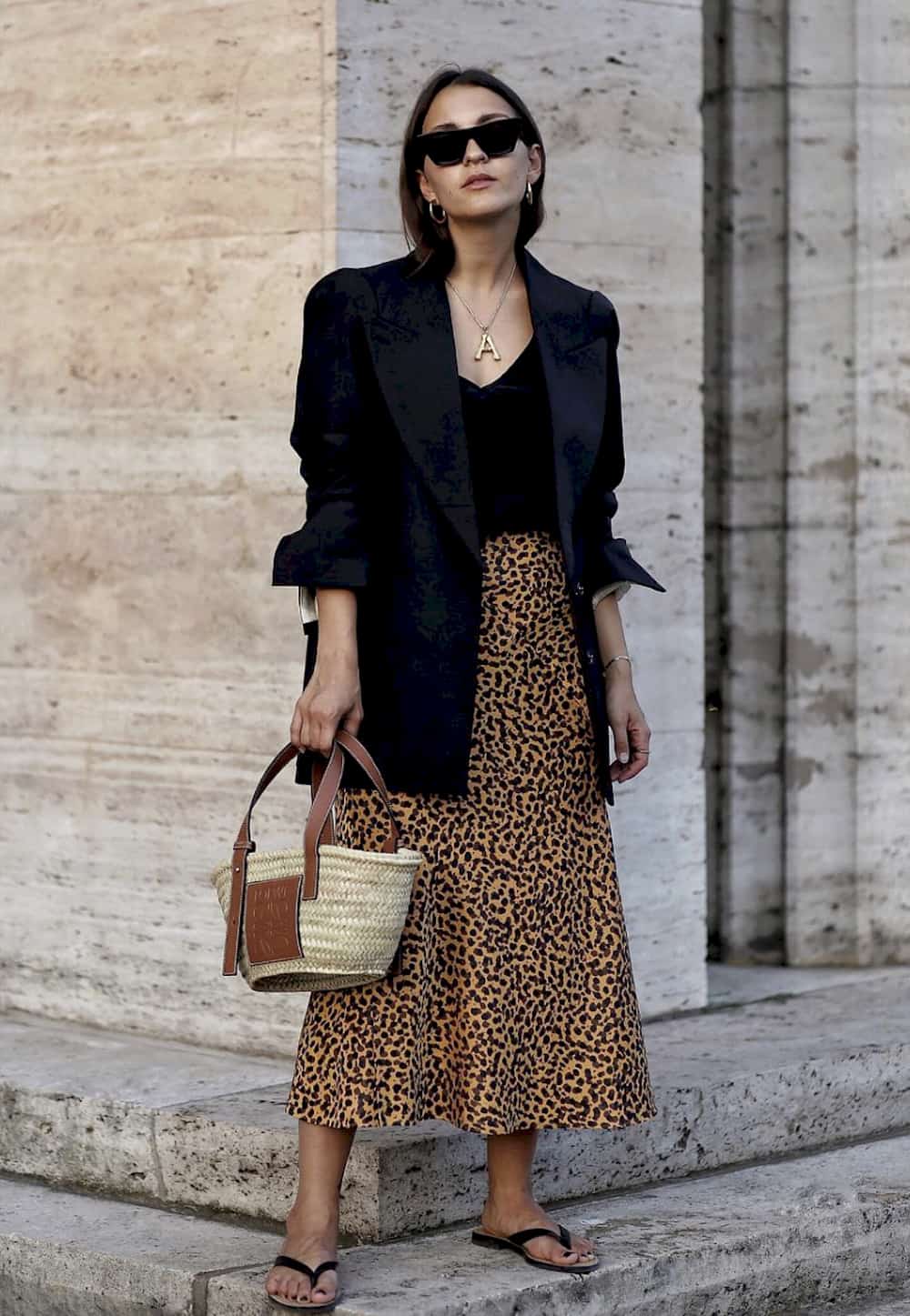 image of a woman in a black blazer, leopard skirt, and black top, with a basket bag purse