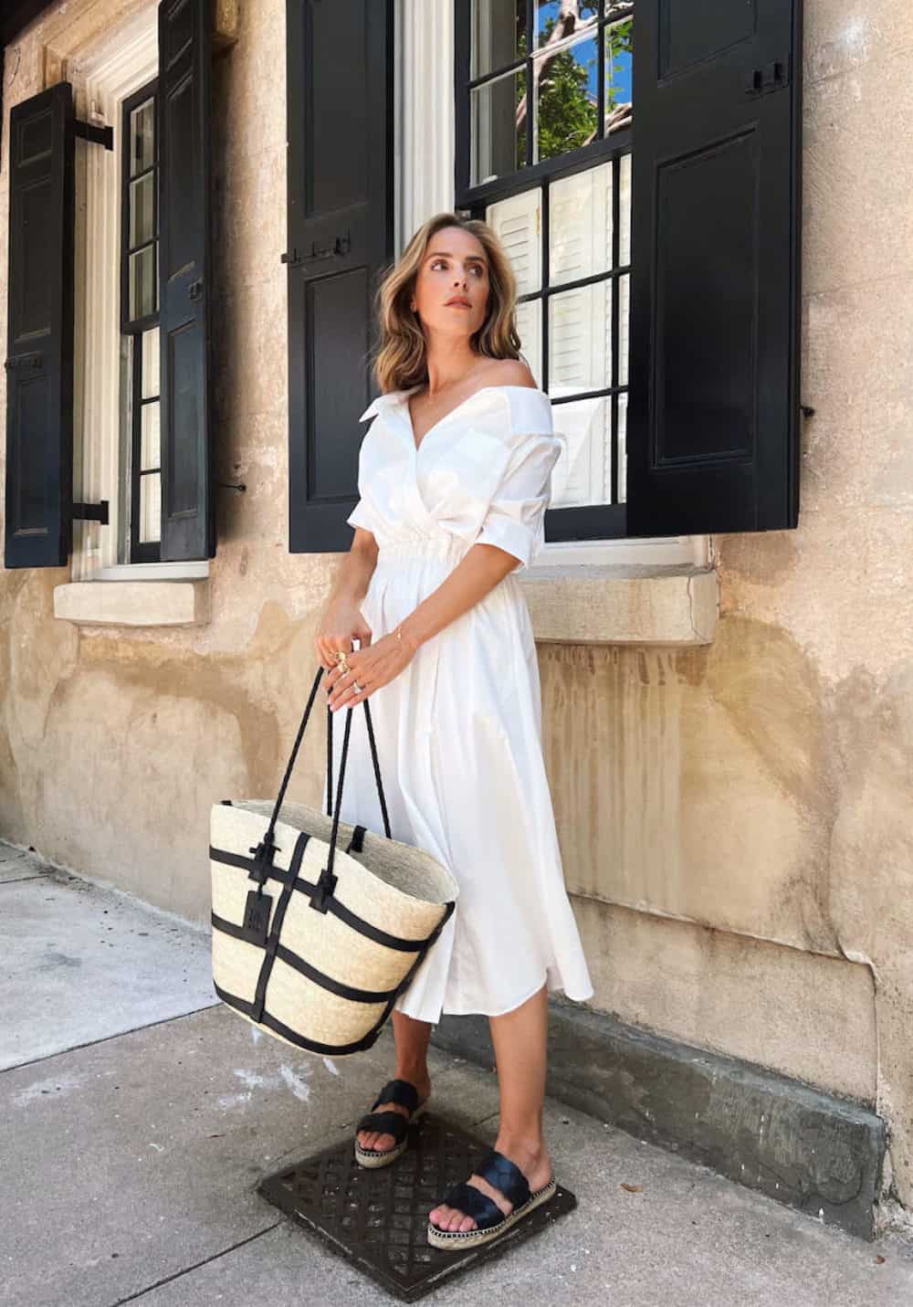 image of a woman wearing a white cotton t-shirt midi dress and black sandals with a straw tote bag