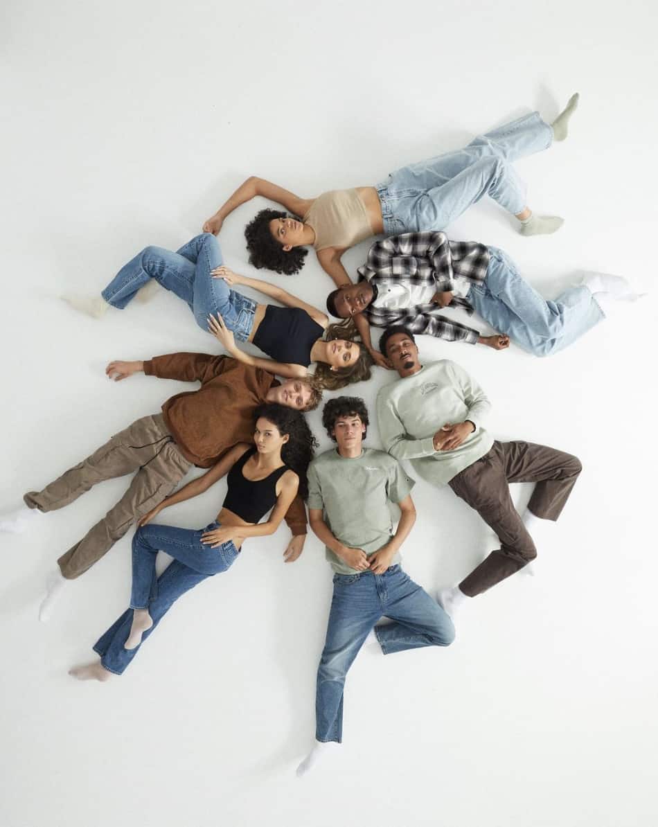 overhead photo of a group of guys and girls wearing jeans and t-shirts laying on the floor