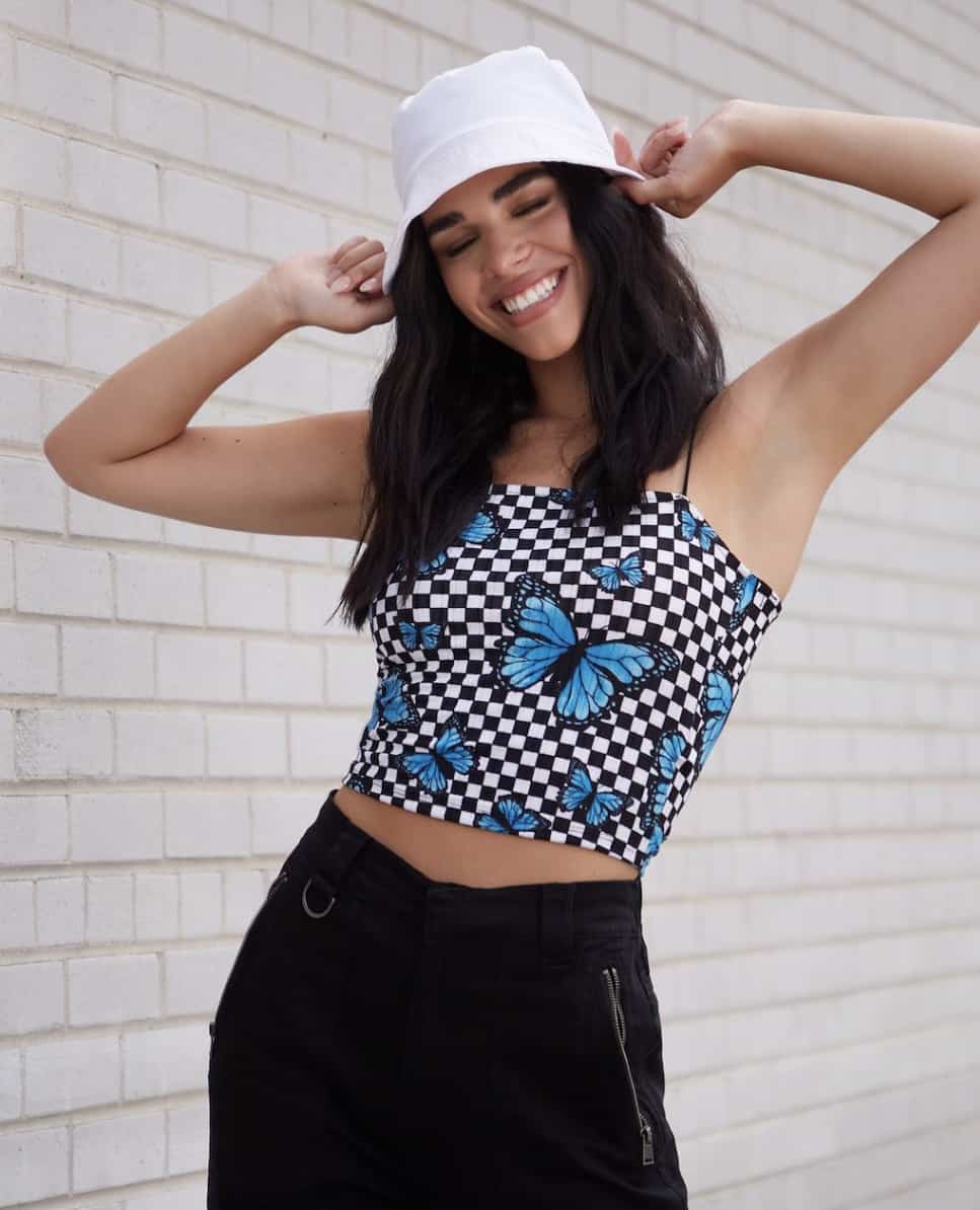 image of a woman in a blue butterfly tube top shirt and black pants with a white bucket hat