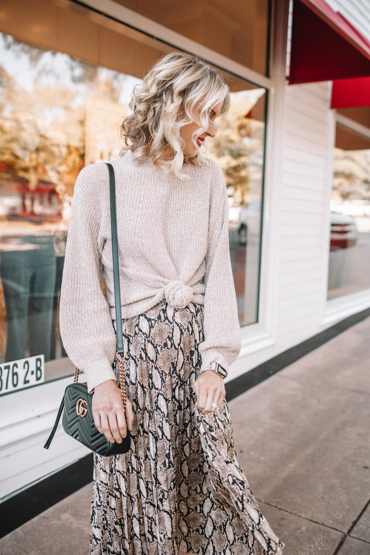 Woman wearing a knotted sweater over a dress.