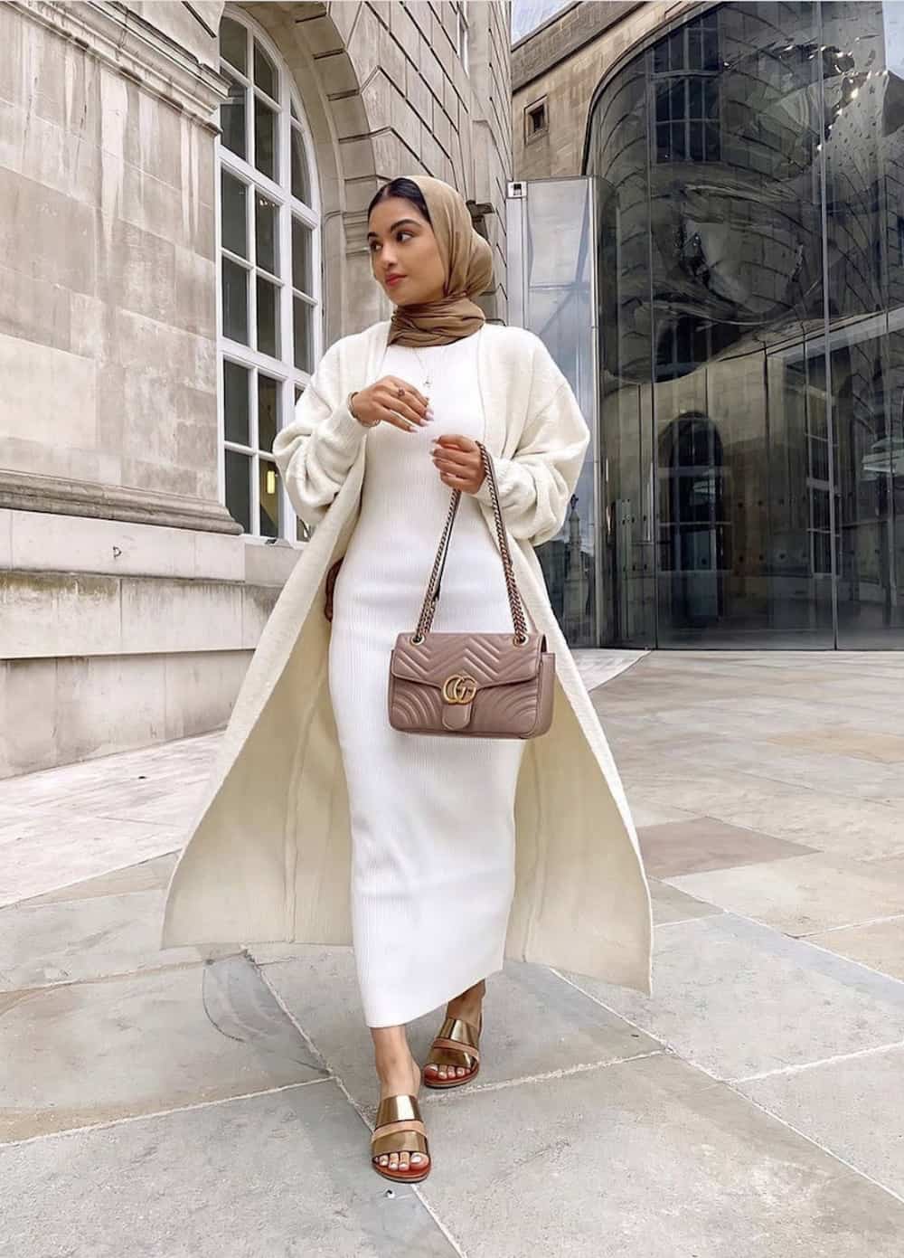 image of a woman wearing a head scarf, a white knit midi dress and a pair of metallic gold sandals 