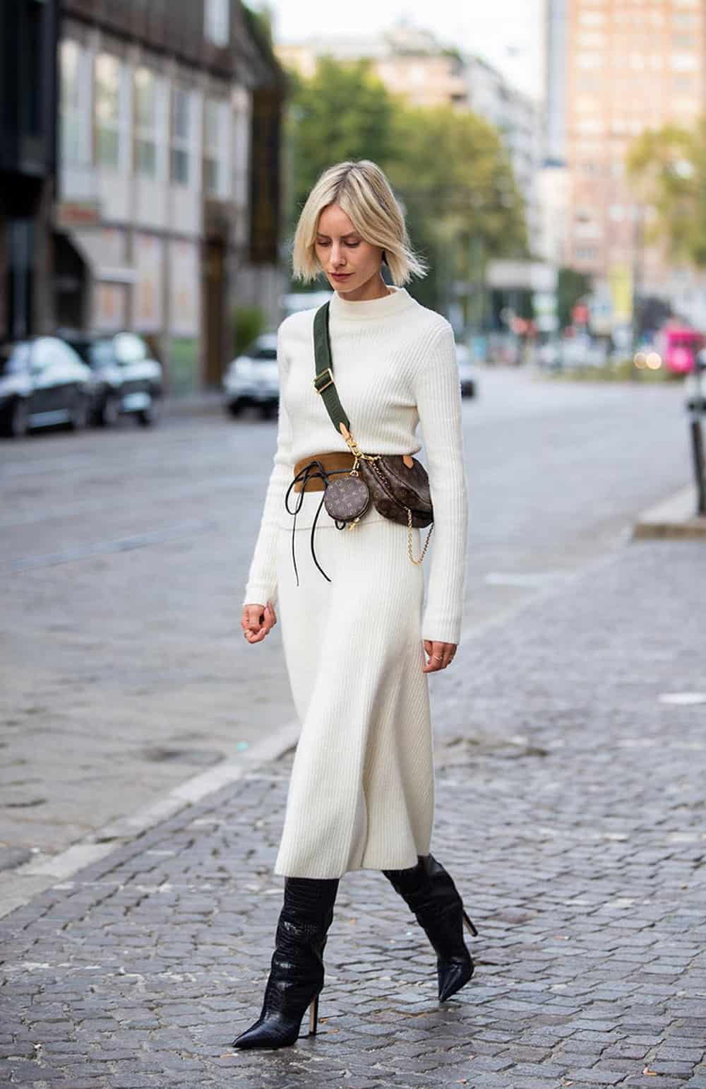 image of a blonde woman wearing a long sleeve midi-length sweater dress in a white color and black slouchy boots