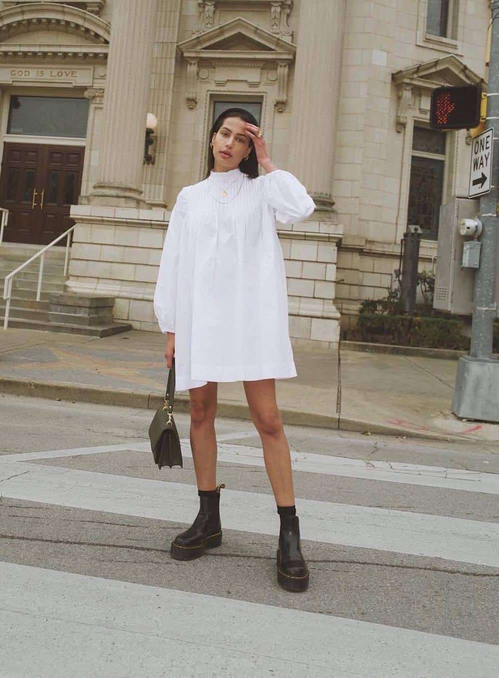 image of a woman with dark hair in a mock neck white dress with long puff sleeves and black ankle lug boots