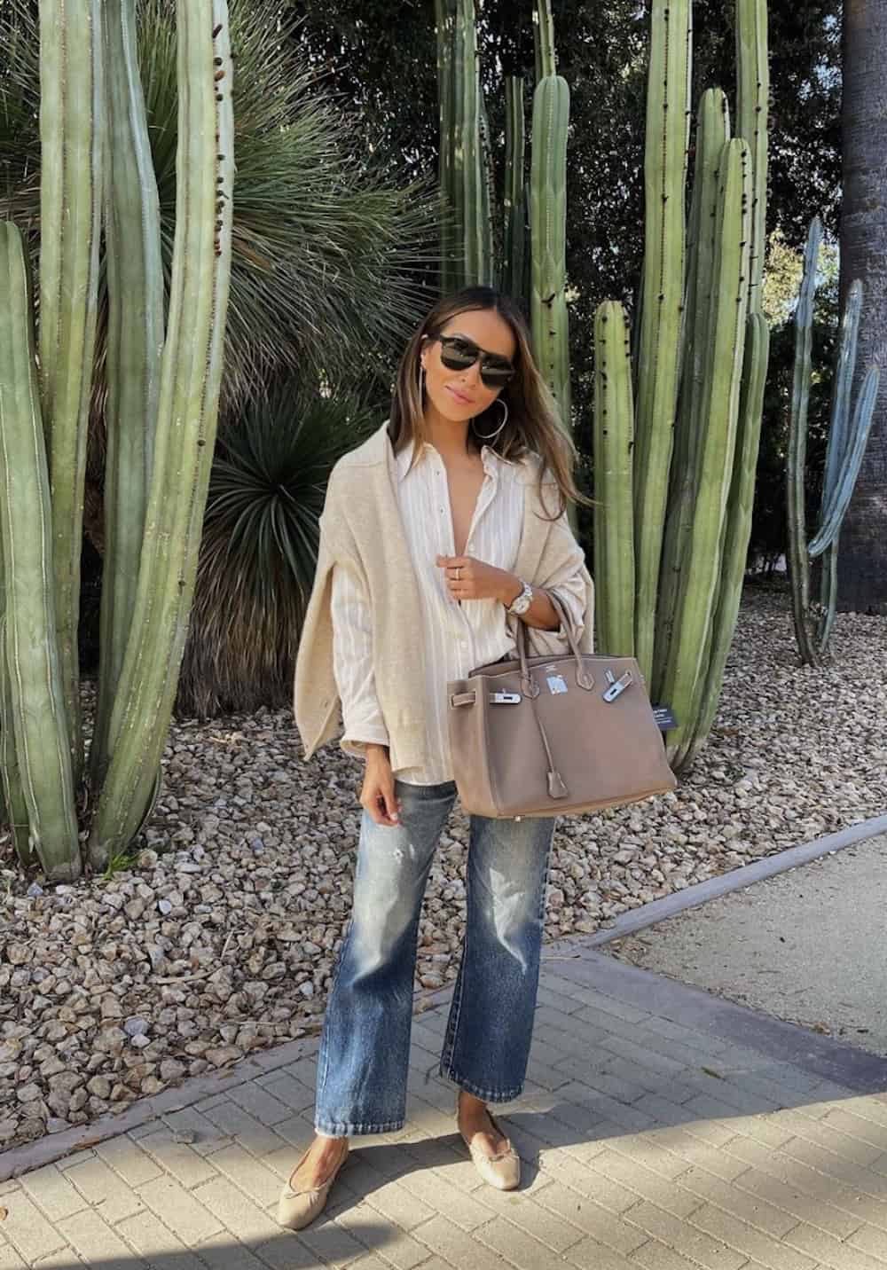 image of a woman in a white shirt, blue jeans, ballet flats, and carrying a taupe Birkin bag