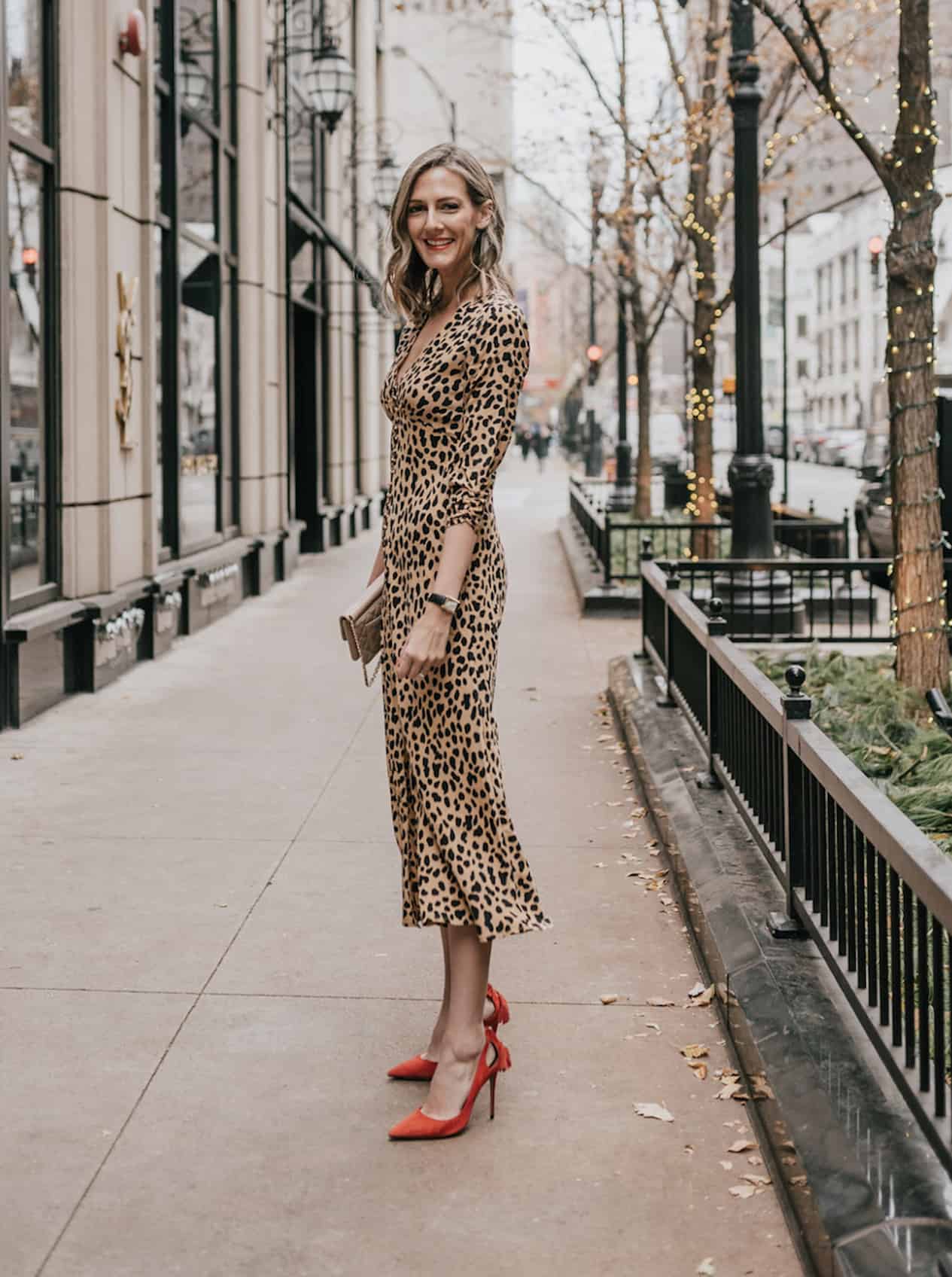 Woman wearing red pumps and a silk leopard print wrap dress.