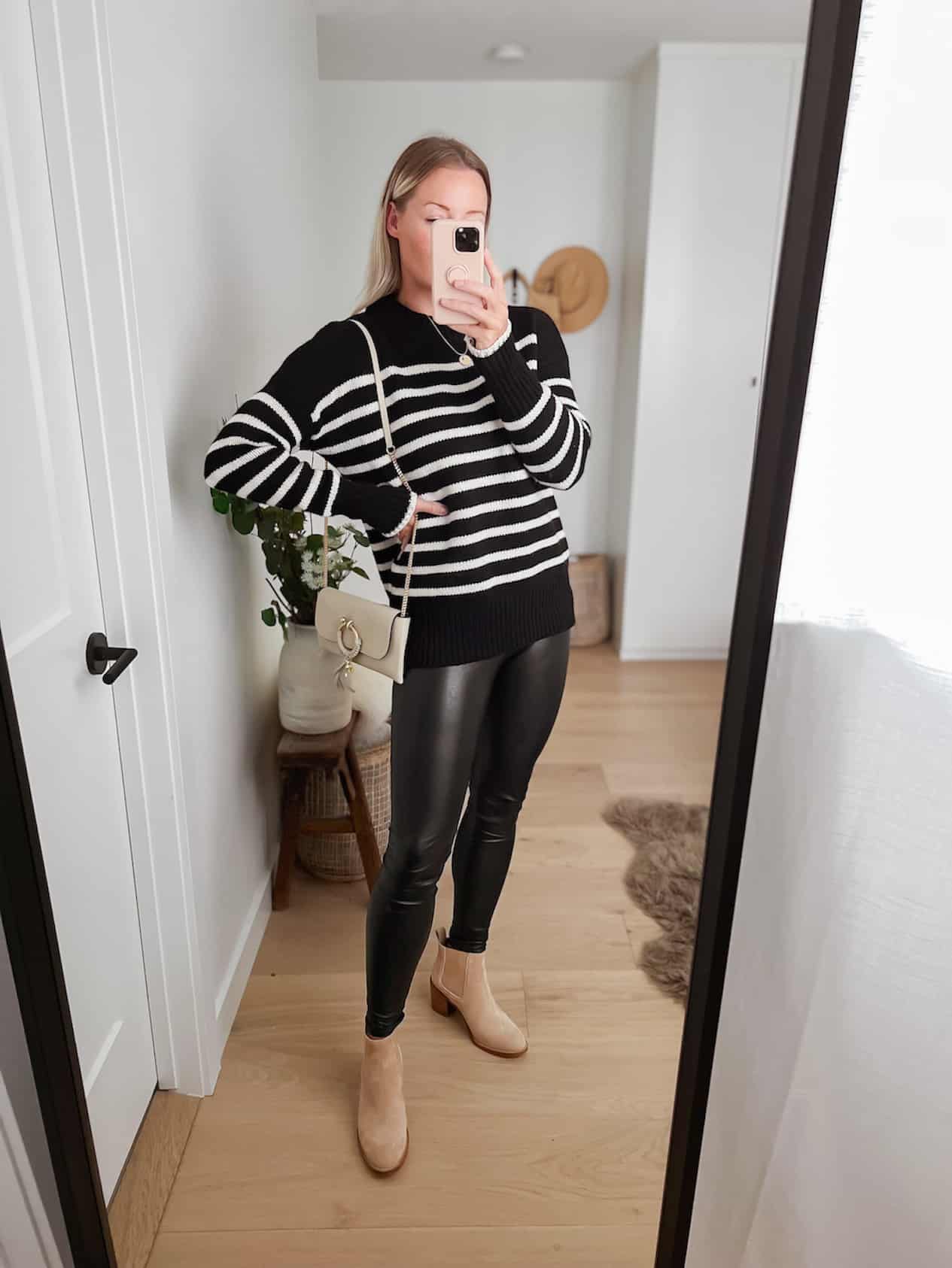 Woman wearing black leather leggings and a black and white striped sweater.