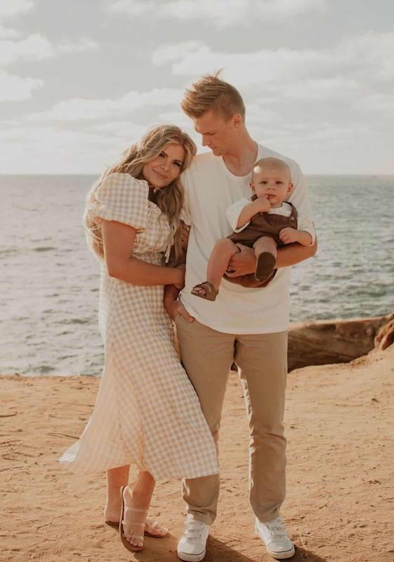 image of a man, woman, and a baby in beige outfits at the beach