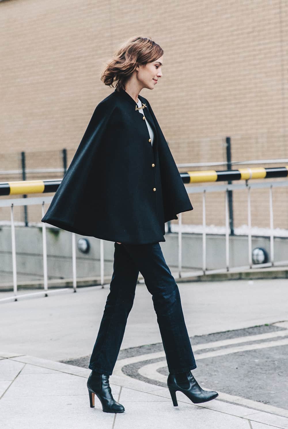 image of a woman in a dark cape poncho top with jeans and black booties