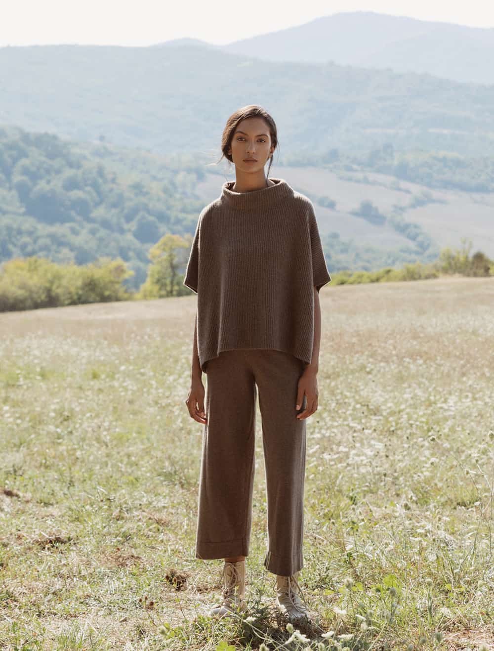 image of a woman standing in a field wearing a matching brown cashmere poncho and wide leg pants set
