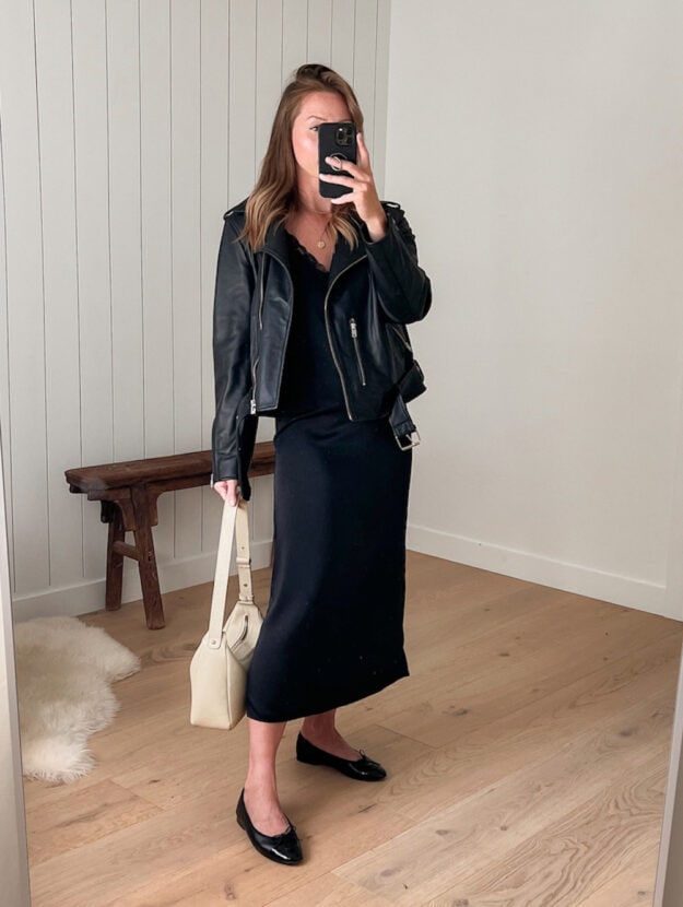 woman wearing a black leather jacket over a black slip dress with black Chanel ballet flats