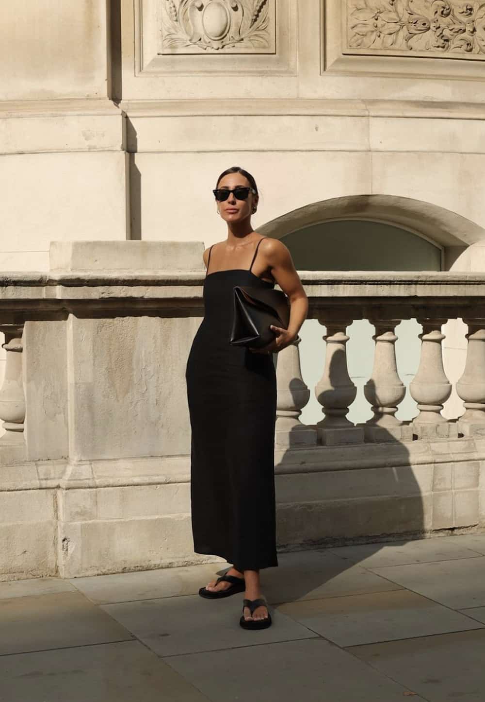 Woman wearing a black dress and flip flops.