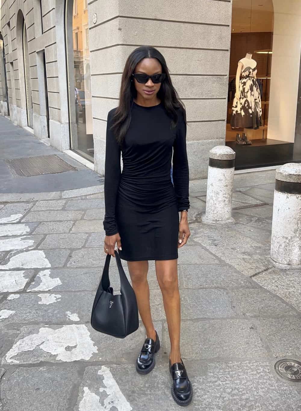 Woman wearing a knit, black dress and loafers.