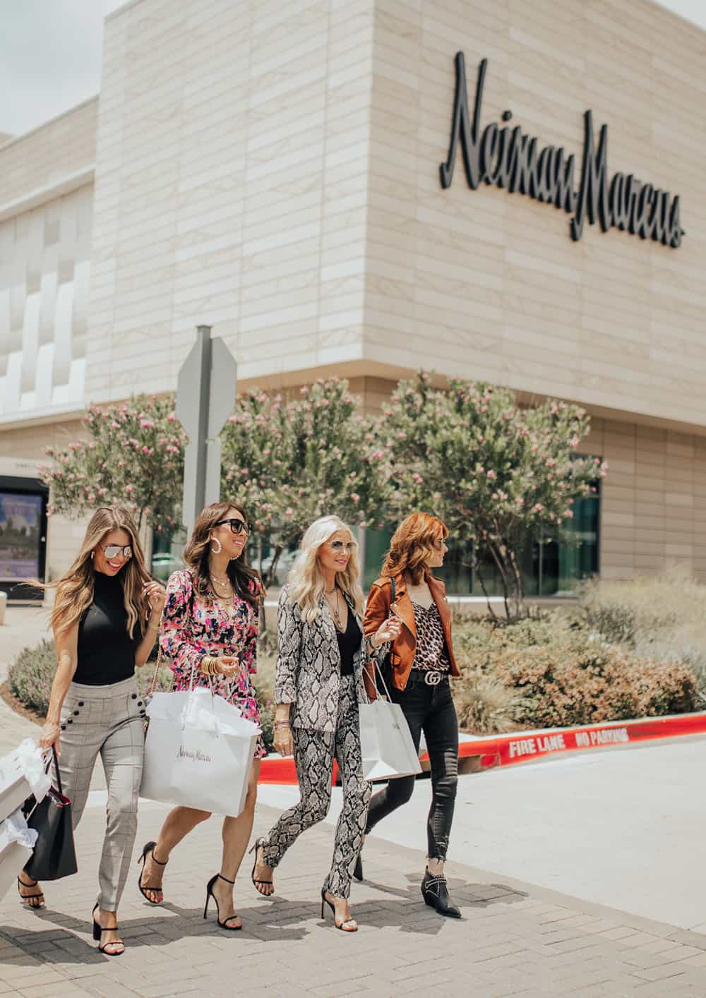 image of four fashionable women walking in front of a Neiman Marcus store