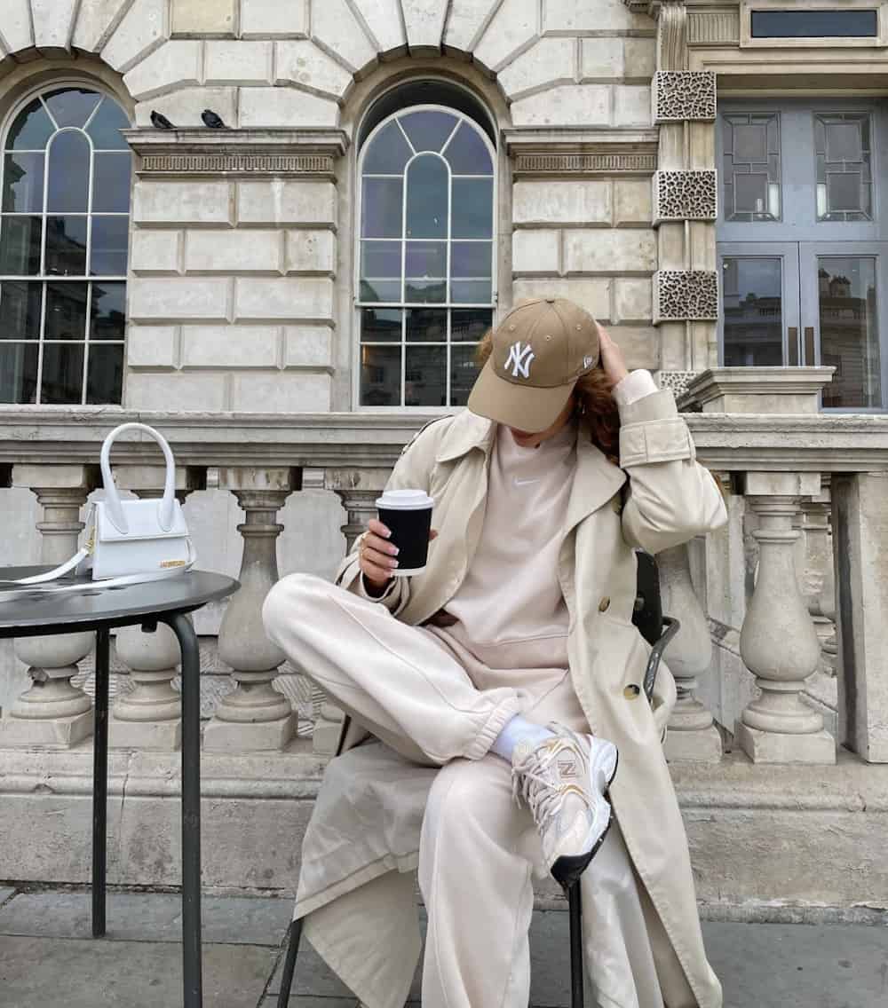Woman wearing neutral colored athleisure and drinking coffee.