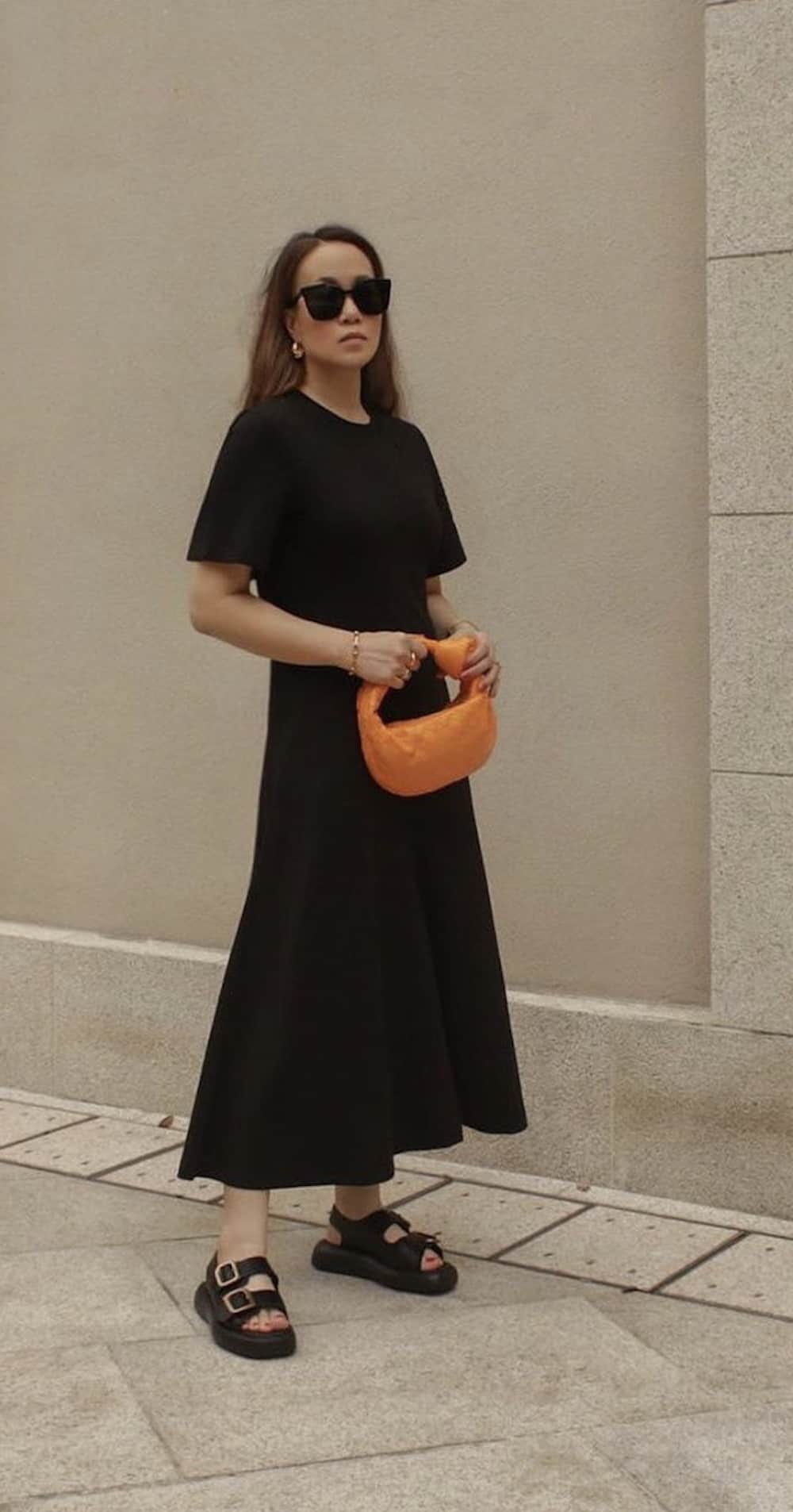 Woman wearing a black tshirt dress and sandals.