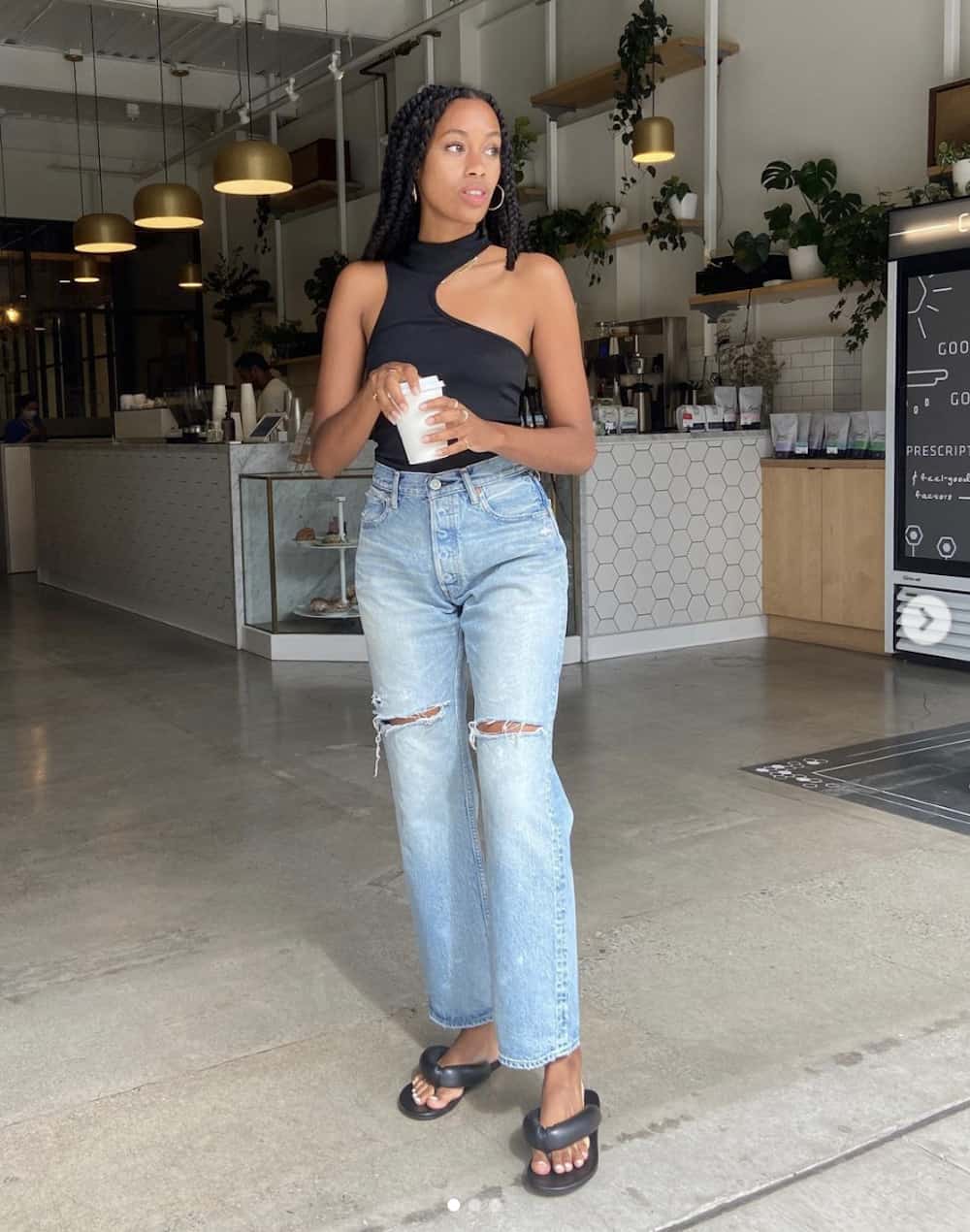 image of a black woman in a black tank top, straight leg jeans, and black thong sandals