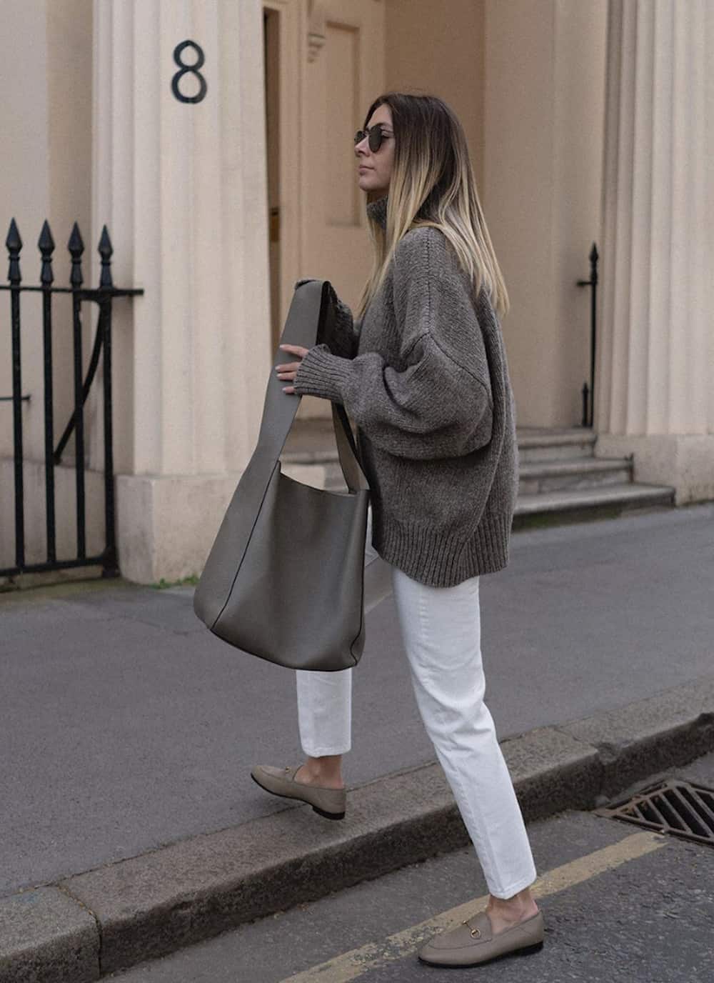 image if a woman in an oversized taupe sweater, white straight leg jeans, and taupe loafers