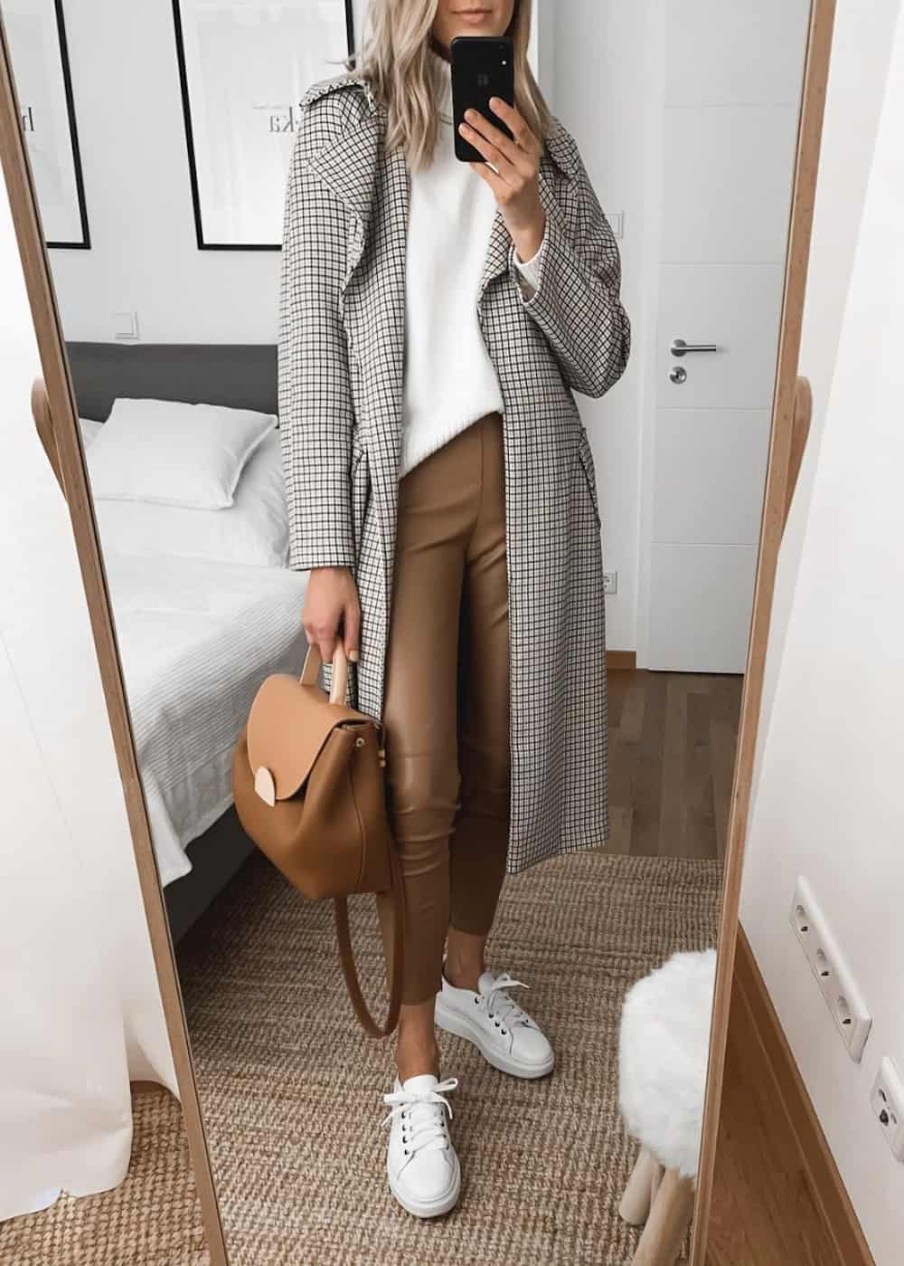 image of a woman in brown leather leggings, a plaid long jacket, white sweater, and white sneakers 