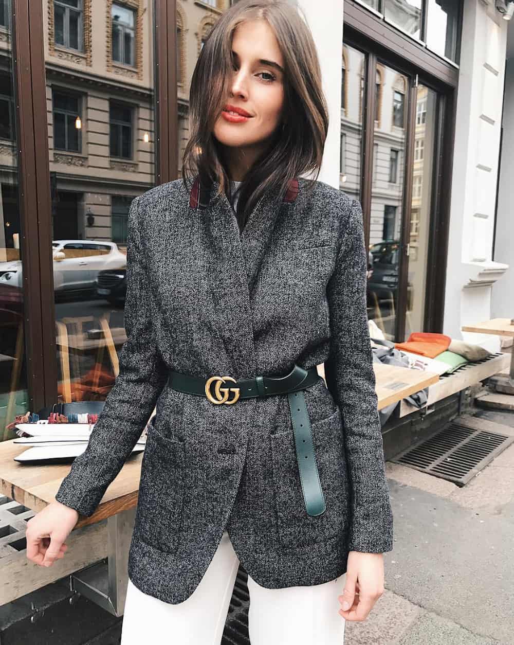 image of a woman wearing a grey blazer with a Gucci belt around the waist and white trousers