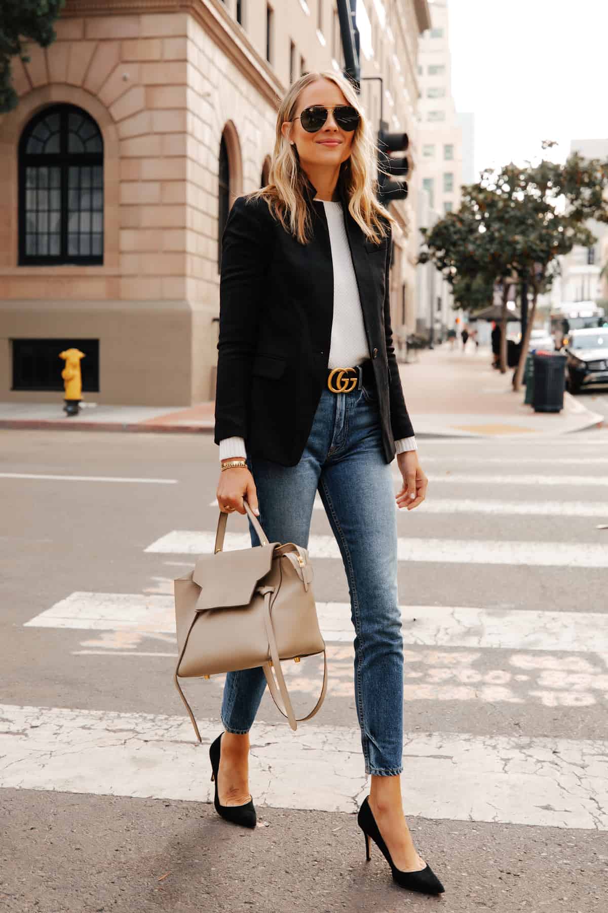 image of a woman wearing a black blazer, white top, jeans with a Gucci belt and black pumps
