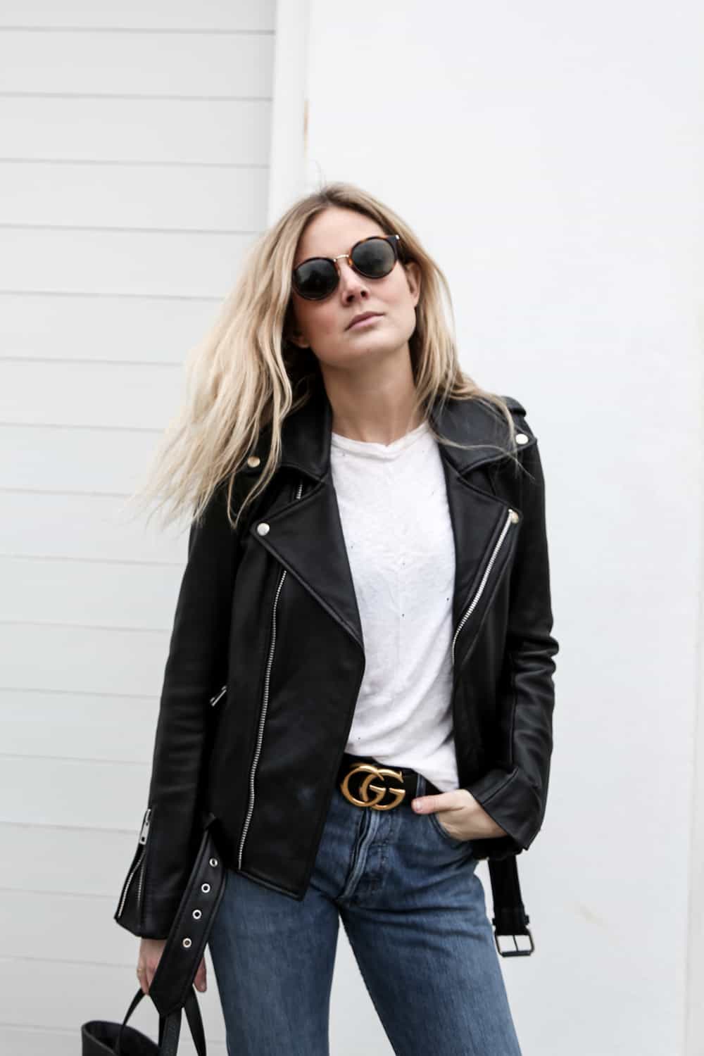 image of a woman wearing a leather jacket, white t-shirt, black Gucci belt, and blue jeans