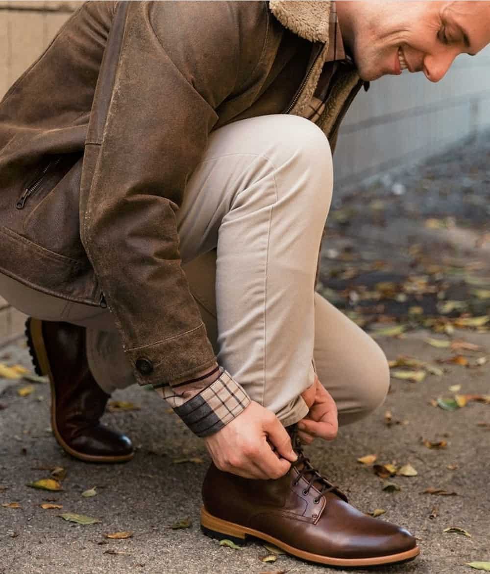 image of a man bending down to tie his brown leather boots