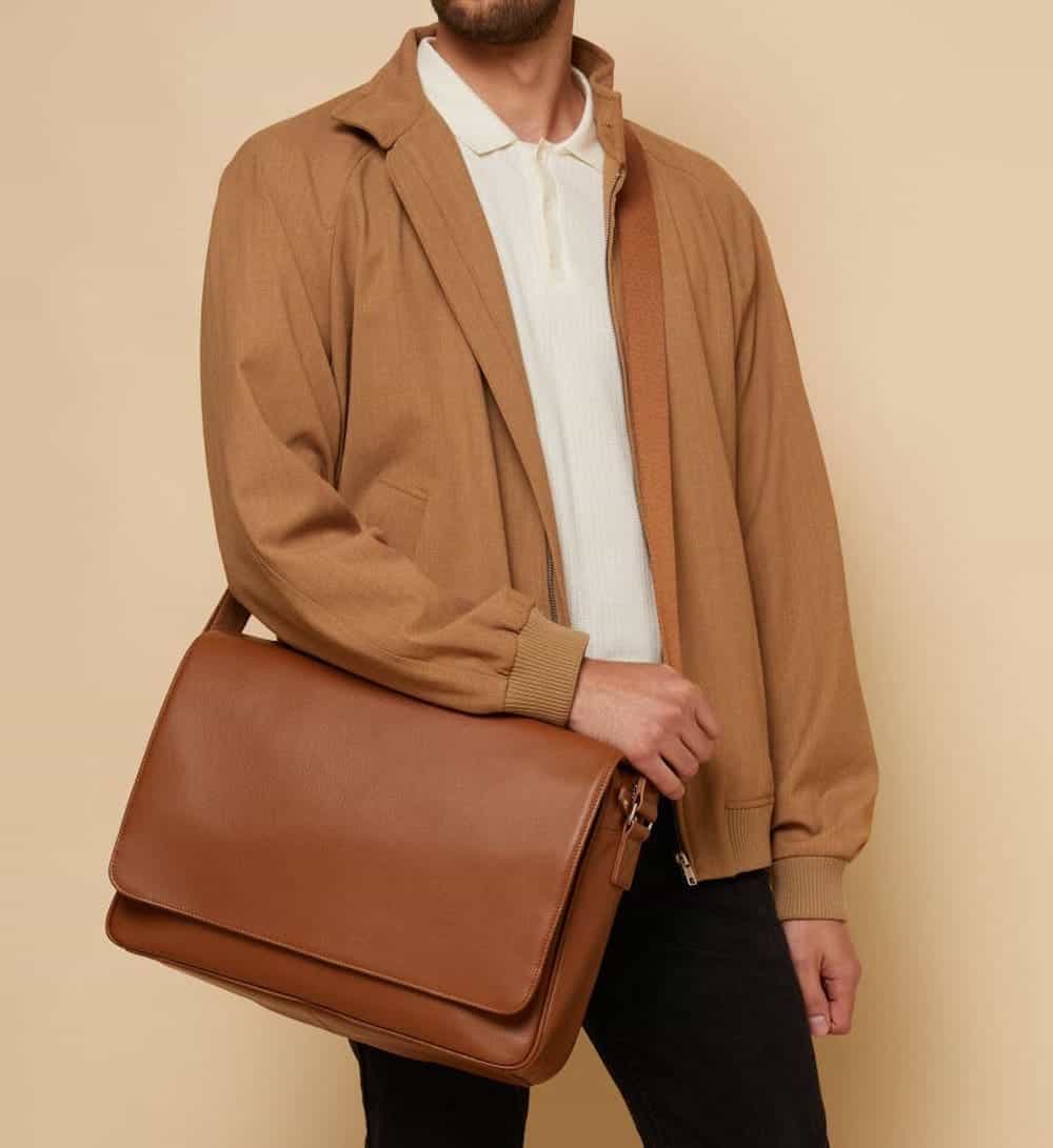 image of a man wearing a brown jacket and white t-shirt with a brown leather messenger bag over his shoulder