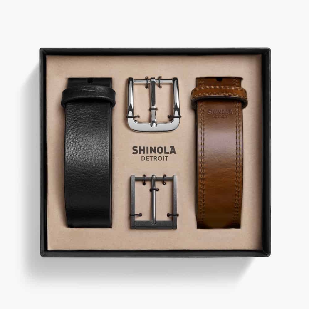 image of a box with two belts inside, one black and one brown, along with two belt buckles