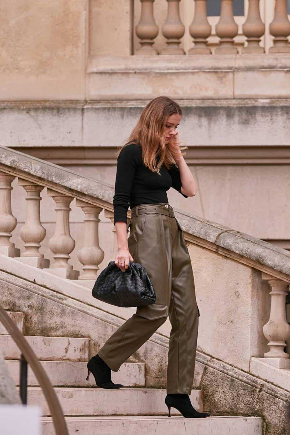 image of a woman wearing green leather pants, a black shirt, and black ankle boots