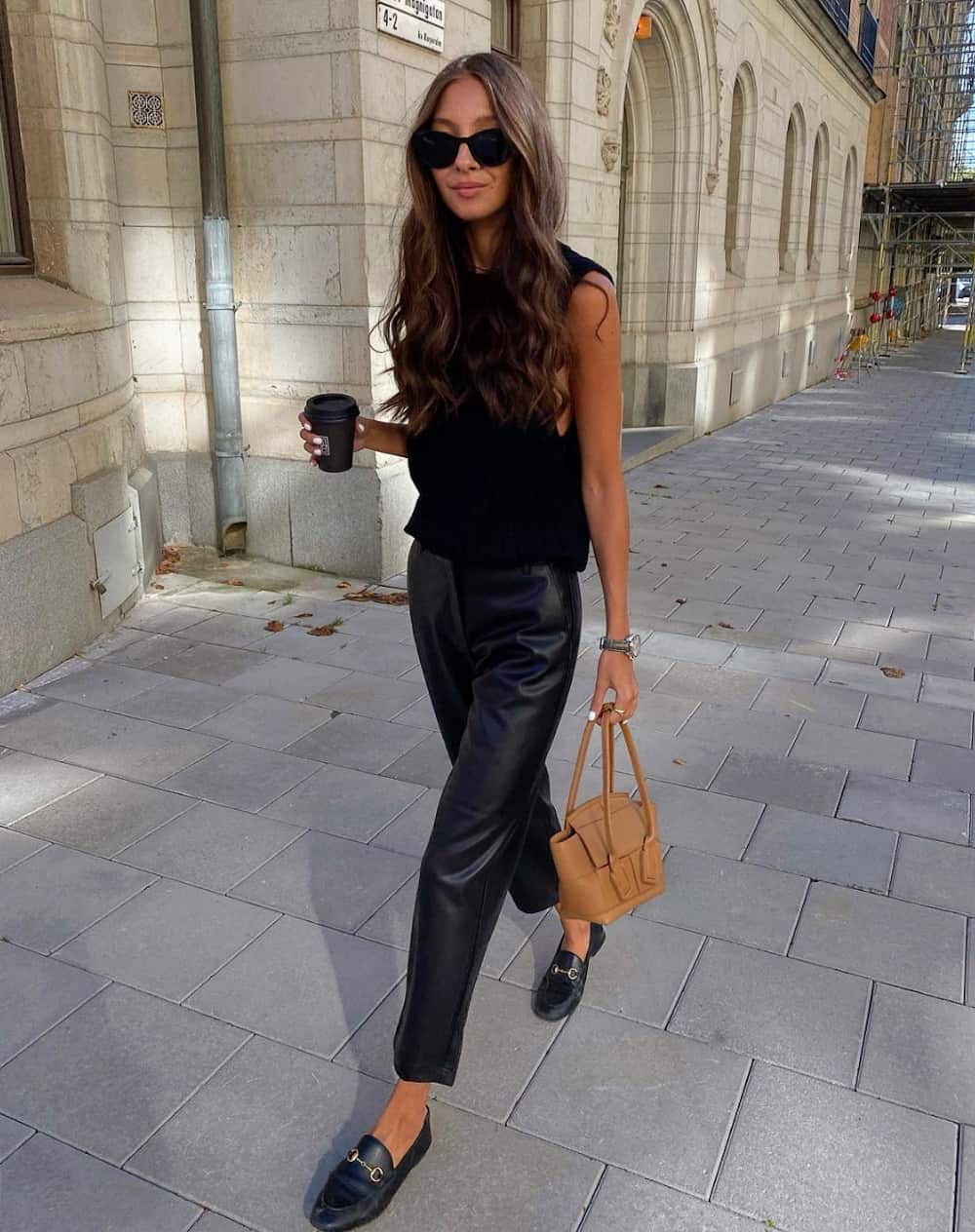 image of a woman wearing a black knit tank top, leather pants, and black leather loafers 