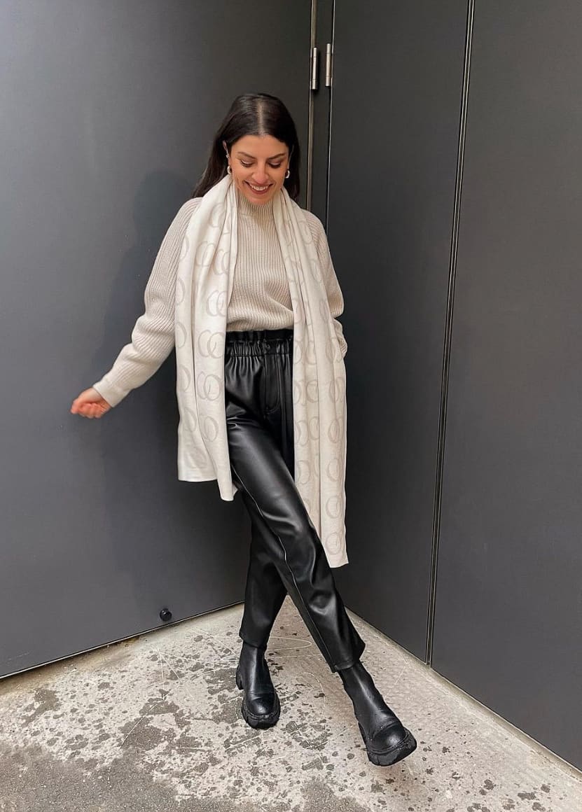 image of a woman wearing black leather pants, lug boots, a black sweater, and a silk scarf