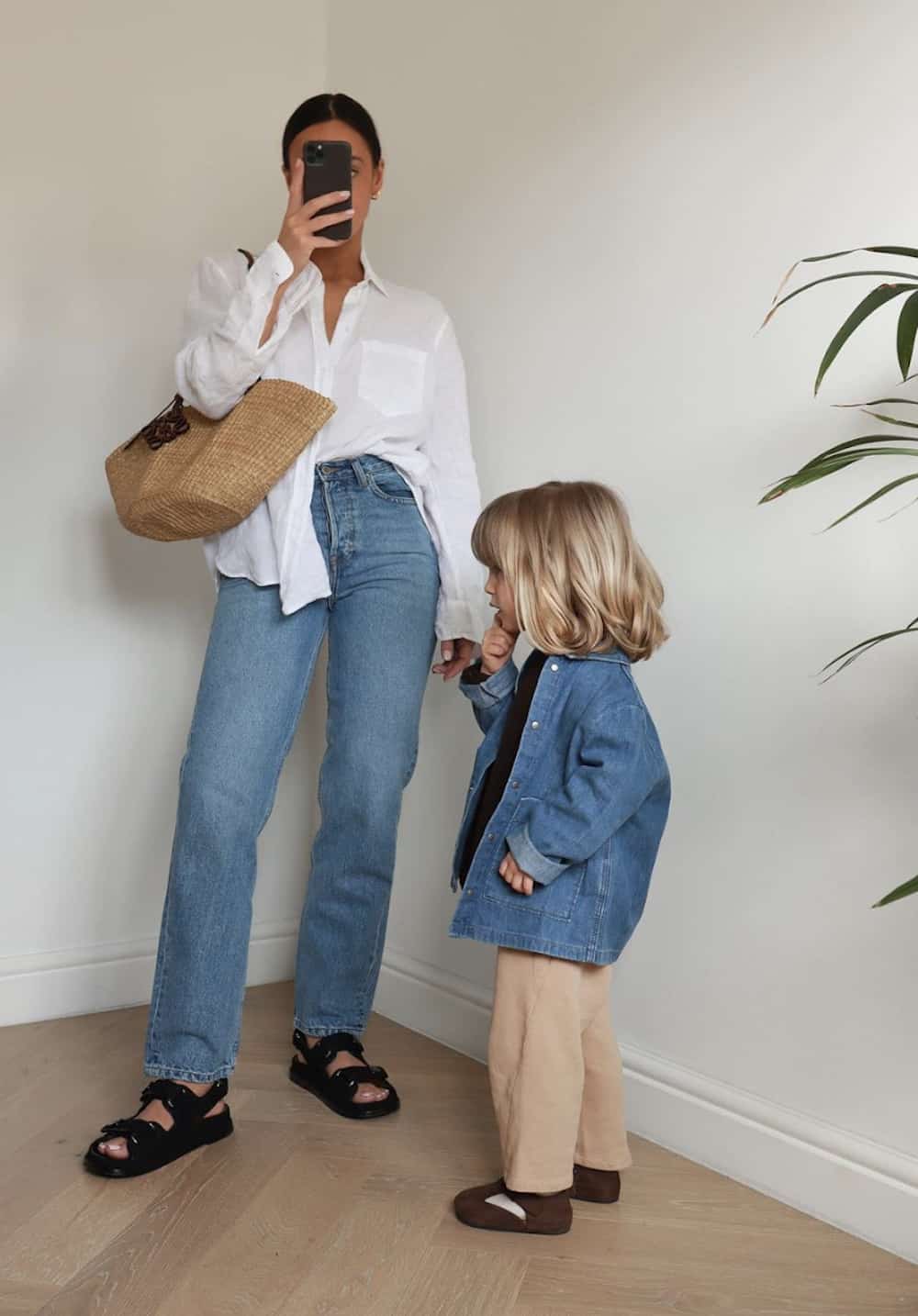 image of a mom and her daughter, she is wearing a white button up shirt, jeans, and black sandals